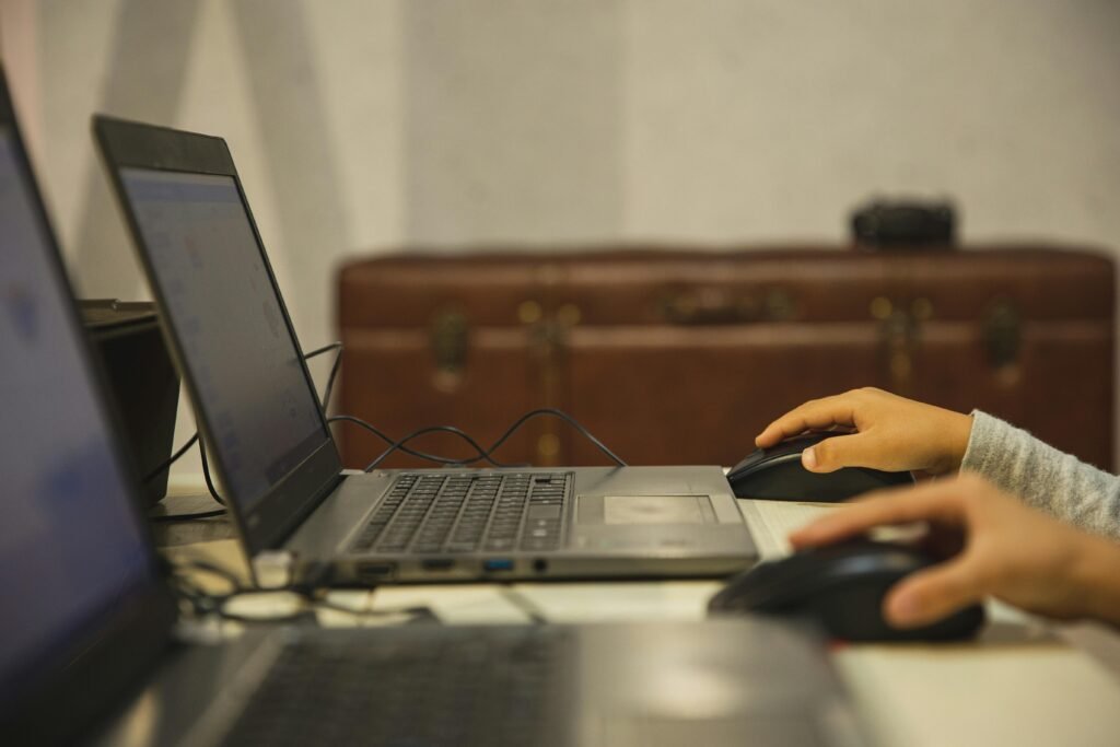 Crop unrecognizable schoolchildren studying together at table with open netbooks during computer class in school